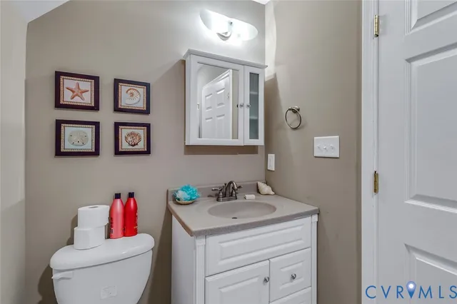 a bathroom with a toilet sink vanity and mirror