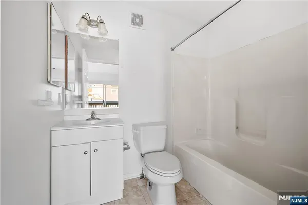 a bathroom with a toilet sink vanity tub and mirror