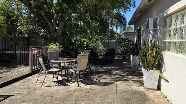 a view of backyard with a table and chairs with wooden fence and plants
