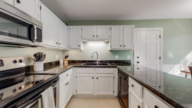a kitchen with granite countertop a stove sink and cabinets
