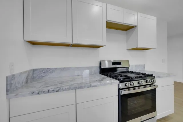a kitchen with stainless steel appliances granite countertop white cabinets and a stove