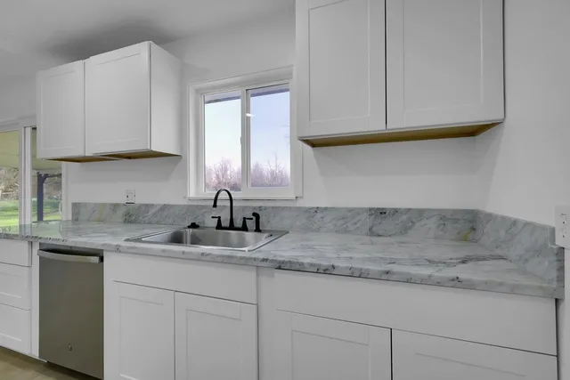 a kitchen with granite countertop white cabinets and a sink
