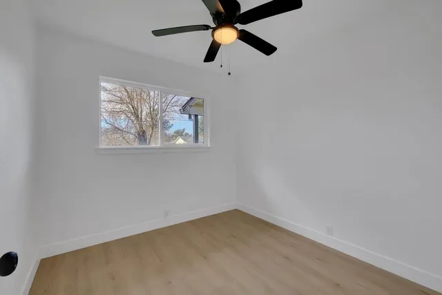 an empty room with ceiling fan and window