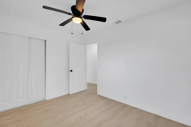 an empty room with a window and a fan