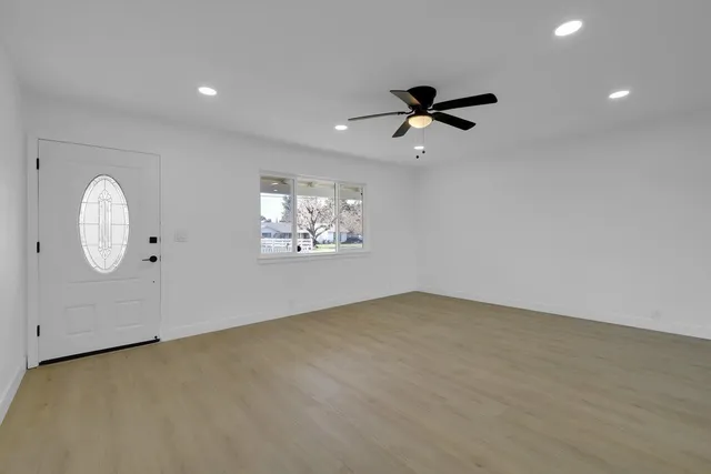 an empty room with windows and fan