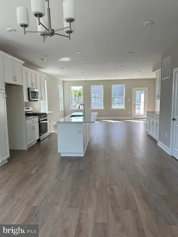 a large kitchen with cabinets wooden floor and stainless steel appliances