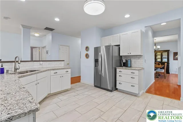 a kitchen with granite countertop white cabinets stainless steel appliances and a counter space