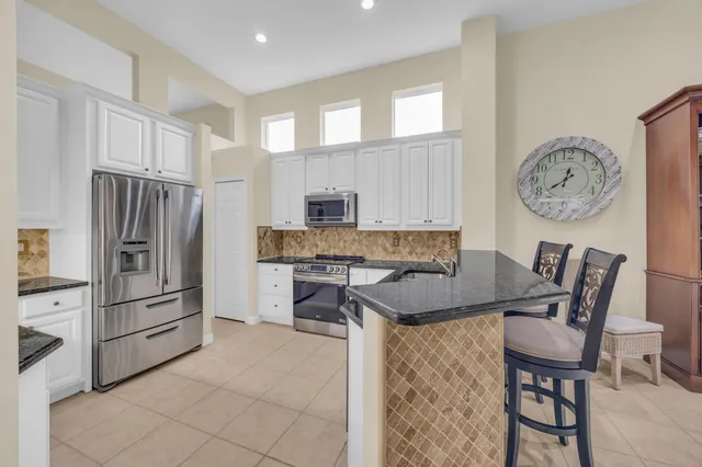 a kitchen with stainless steel appliances granite countertop a stove a refrigerator a oven a white table and chairs