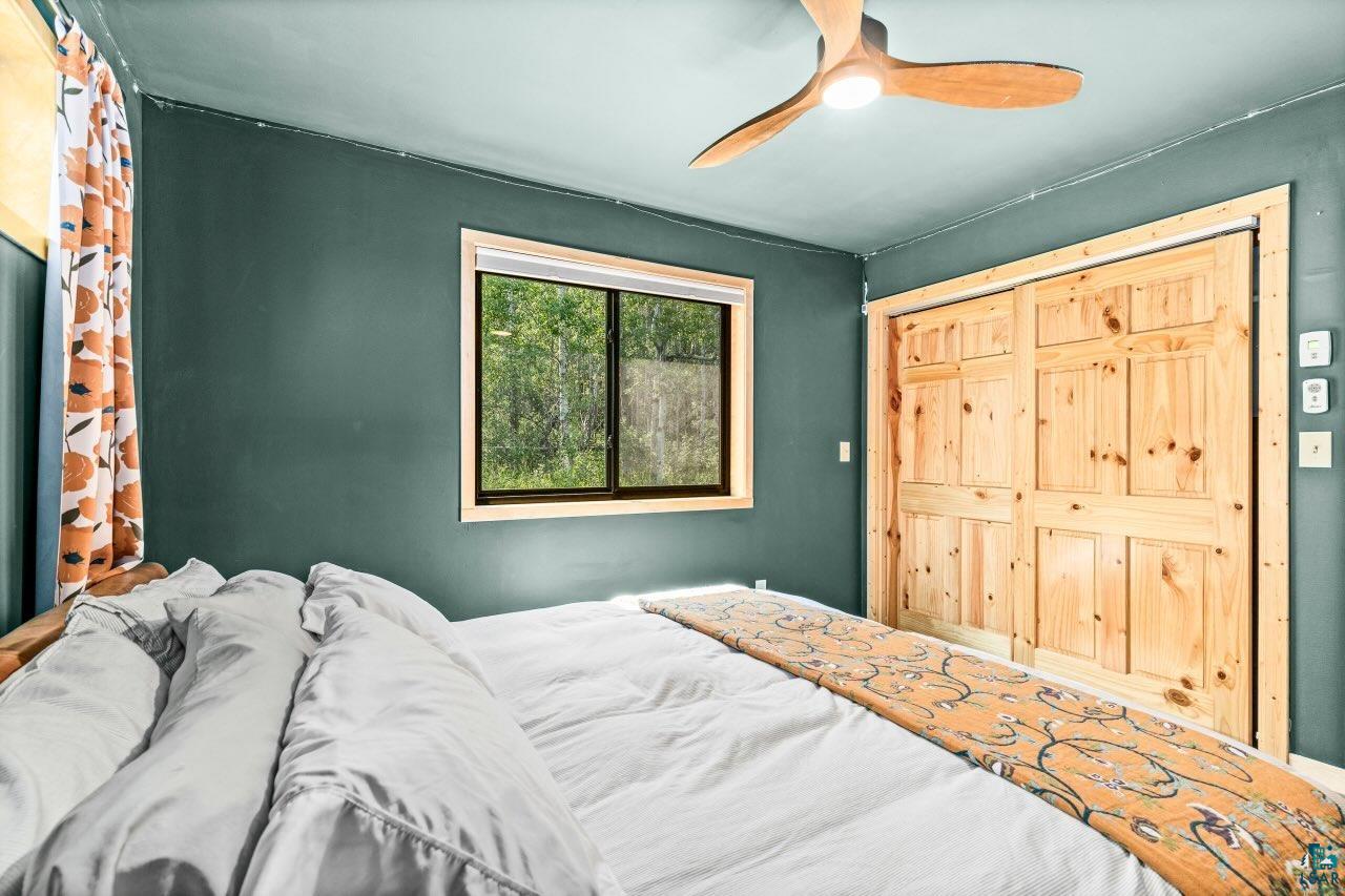 265 Mink Ranch Road Lutsen, MN 55612 - Photo 21 of 33 Room featuring a natural wood-finish ceiling fan, a window with natural wood-finish trim, and natural wood-finish bi-fold walk in closet doors