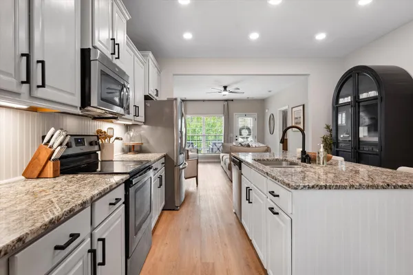 a kitchen with stainless steel appliances granite countertop a sink a stove top oven a counter space and cabinets