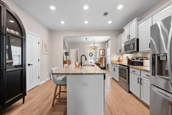 a kitchen with stainless steel appliances granite countertop a refrigerator a stove top oven a sink dishwasher and wooden cabinets with wooden floor