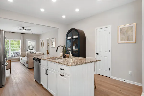 a kitchen with a sink dishwasher a dining table and chairs with wooden floor