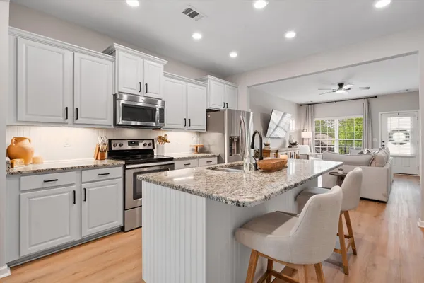 a kitchen with stainless steel appliances granite countertop a stove a sink a microwave a dining table and chairs