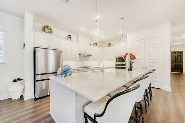 a kitchen with refrigerator a sink a stove and chairs