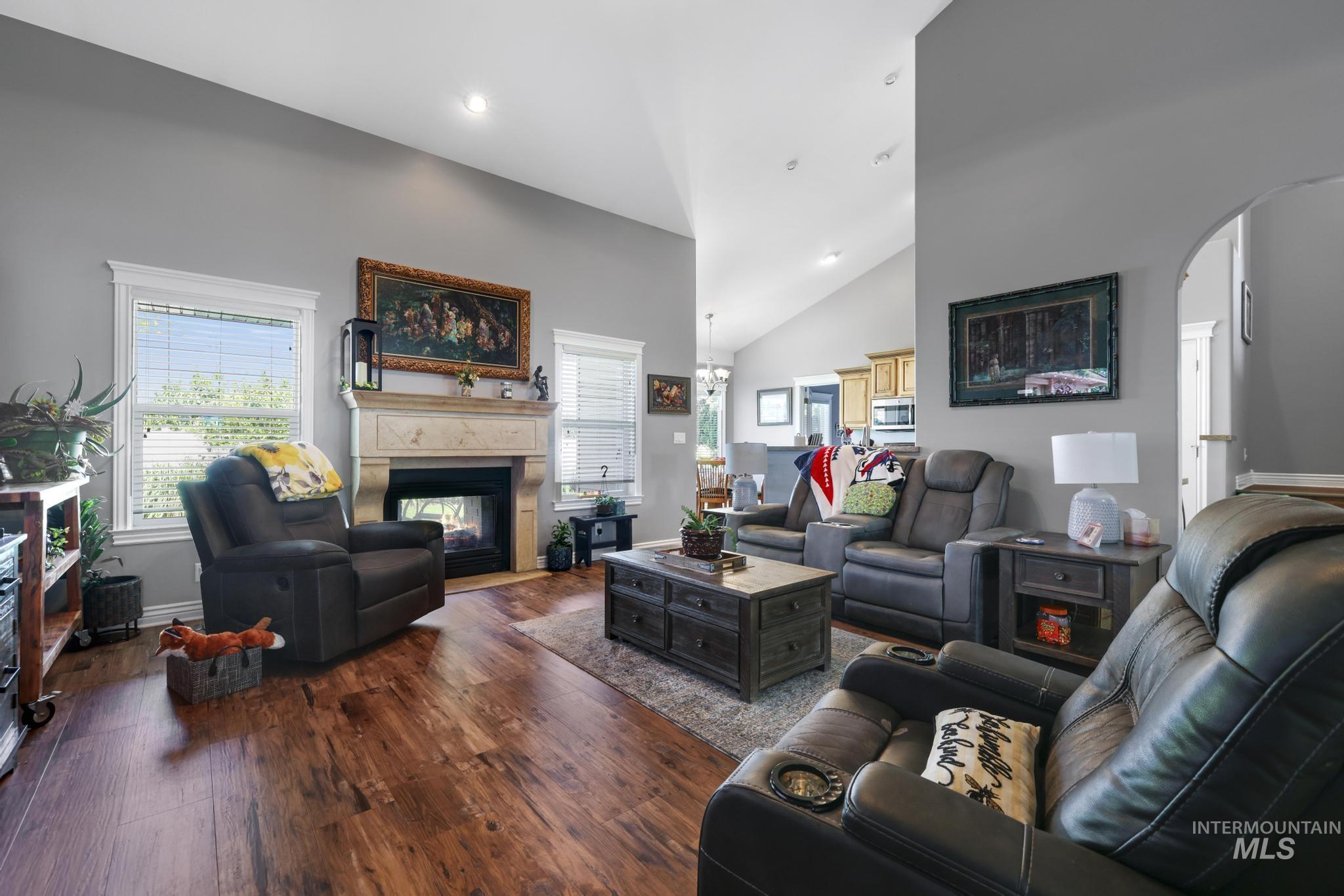 467 Wildrose Loop Twin Falls, ID 83301 - Photo 7 of 46 Spacious living area featuring wood-finish flooring, a stone-mantle fireplace, vaulted ceilings, recessed lighting, and an arched doorway