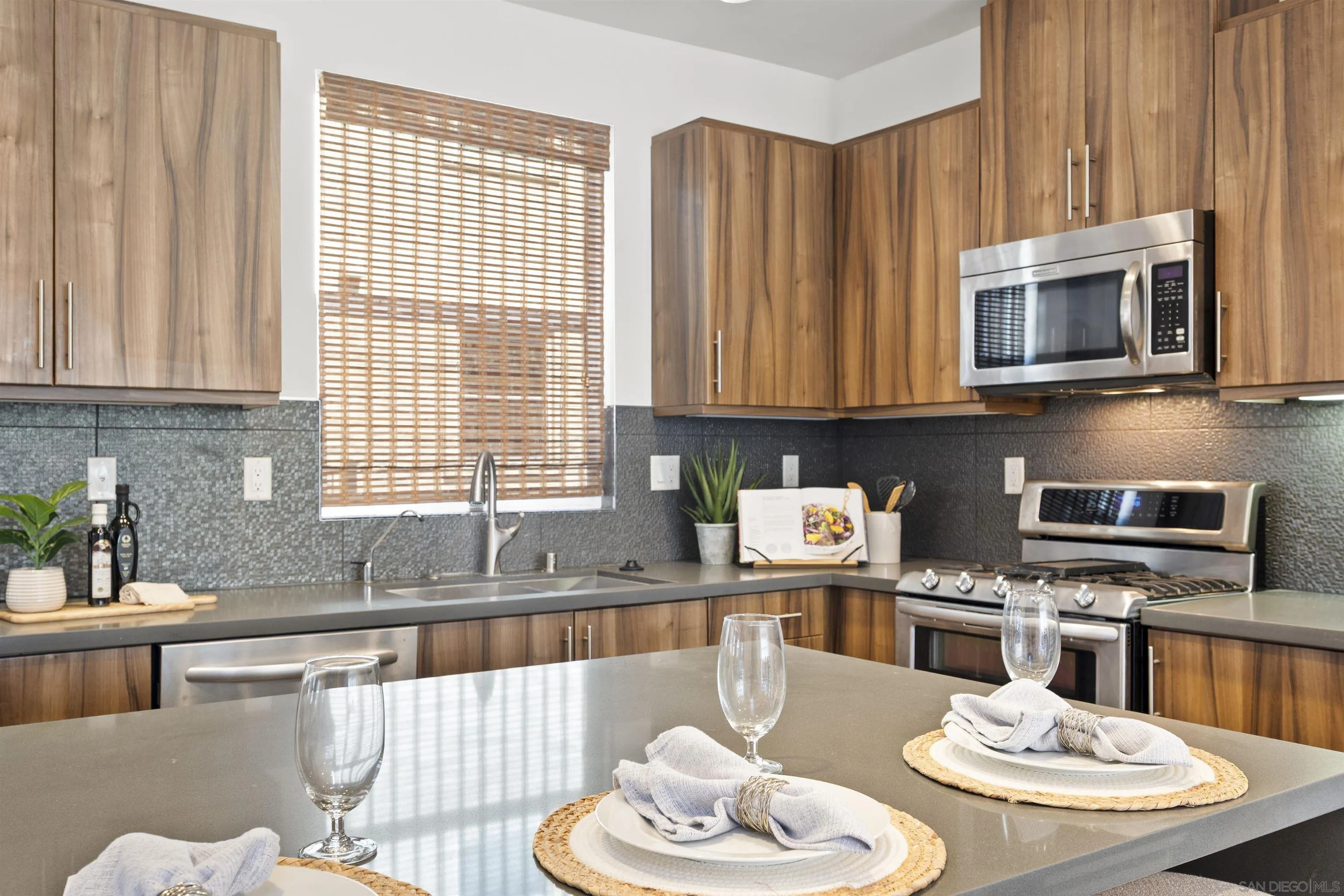 7853 Inception Way San Diego, CA 92108 - Photo 15 of 66 a kitchen with stainless steel appliances kitchen island granite countertop a table chairs stove and microwave