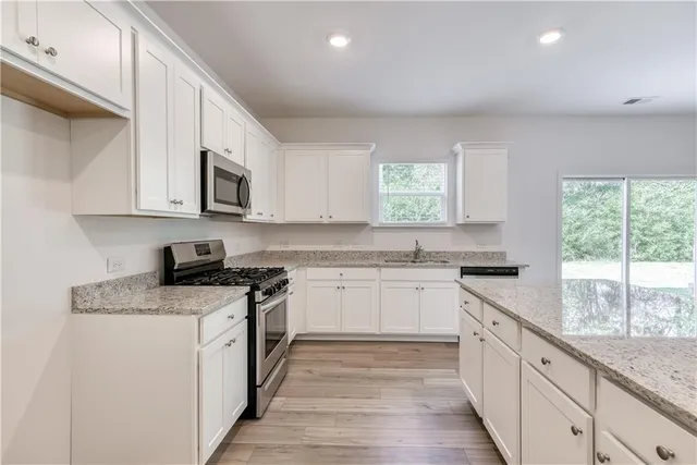 a kitchen with granite countertop white cabinets and white appliances