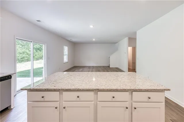 a kitchen with granite countertop white cabinets and a window