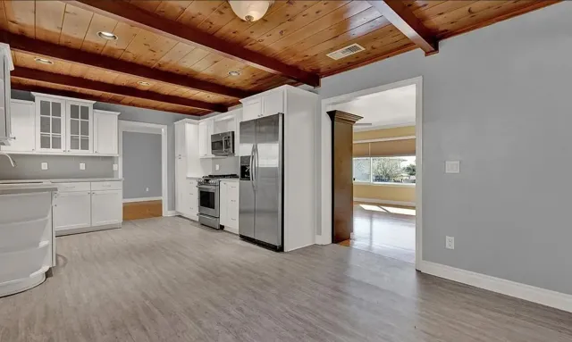 a view of a kitchen with a refrigerator a sink and dishwasher with wooden floor