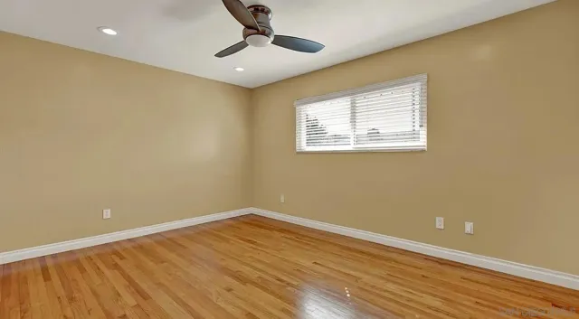a view of empty room with wooden floor and fan
