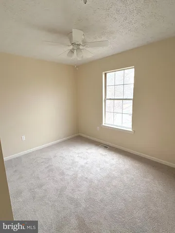 an empty room with a chandelier fan and windows