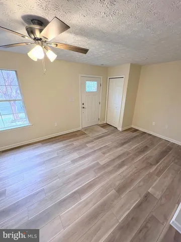 an empty room with wooden floor fan and windows