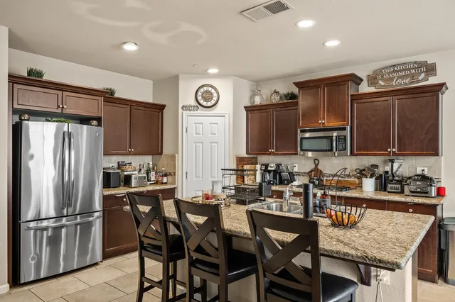a kitchen with stainless steel appliances granite countertop a dining table chairs refrigerator and microwave