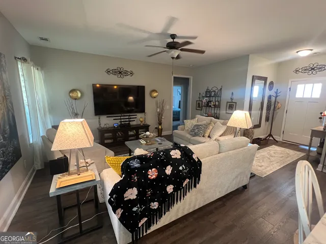 a living room with furniture a flat screen tv and a lamp