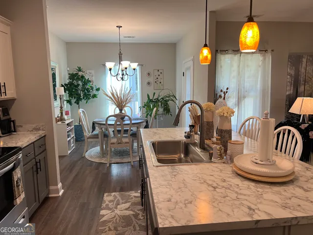 a view of a dining room and kitchen with furniture wooden floor kitchen view and a chandelier