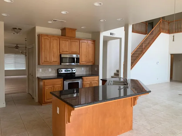a kitchen with kitchen island granite countertop a sink a counter top space appliances and cabinets