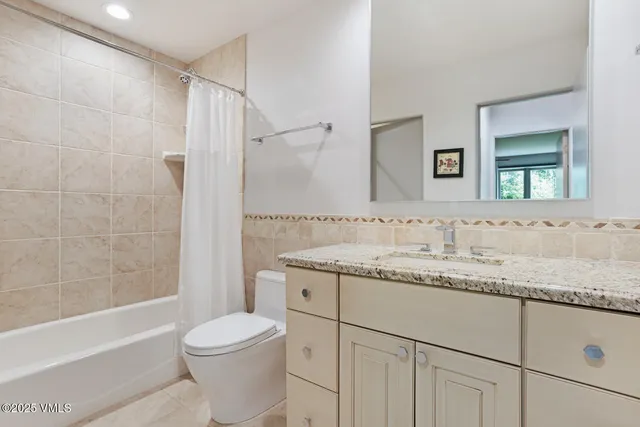 a bathroom with a granite countertop sink toilet vanity mirror bathtub and shower