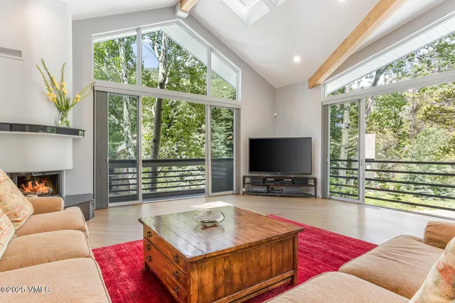 a living room with furniture a flat screen tv and a floor to ceiling window
