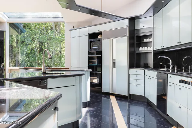 a kitchen with granite countertop a stove a sink and a refrigerator