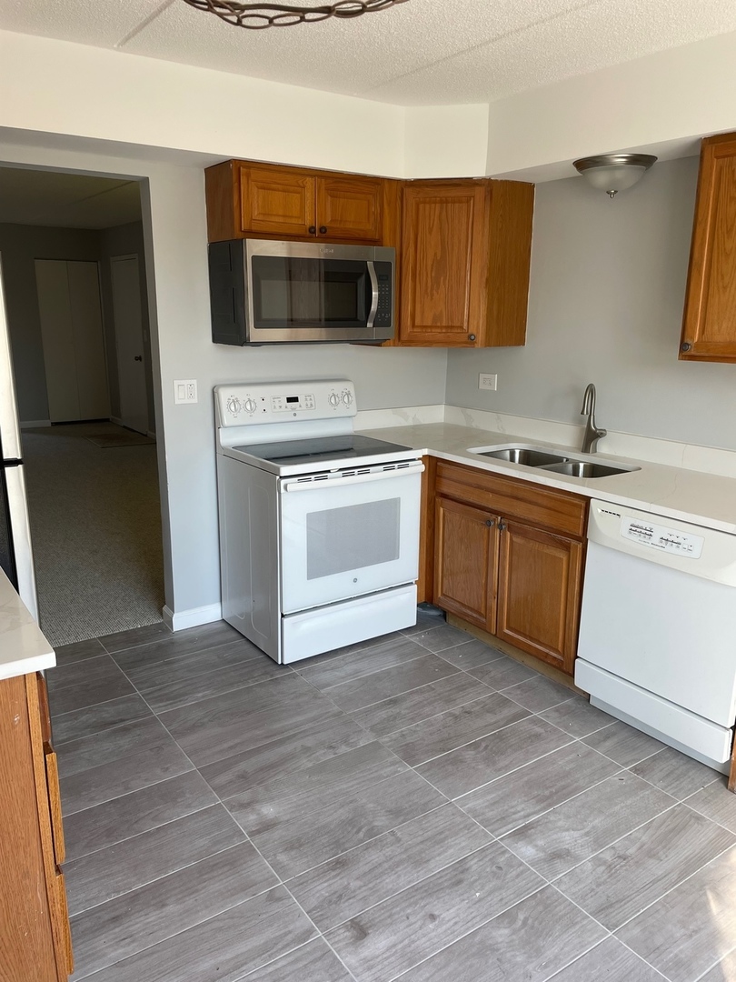 5500 Tinder, Unit 2 Rolling Meadows, IL 60008 - Photo 2 of 14 a kitchen with stainless steel appliances granite countertop a stove top oven a sink dishwasher and a microwave oven on the blue kitchen countertops