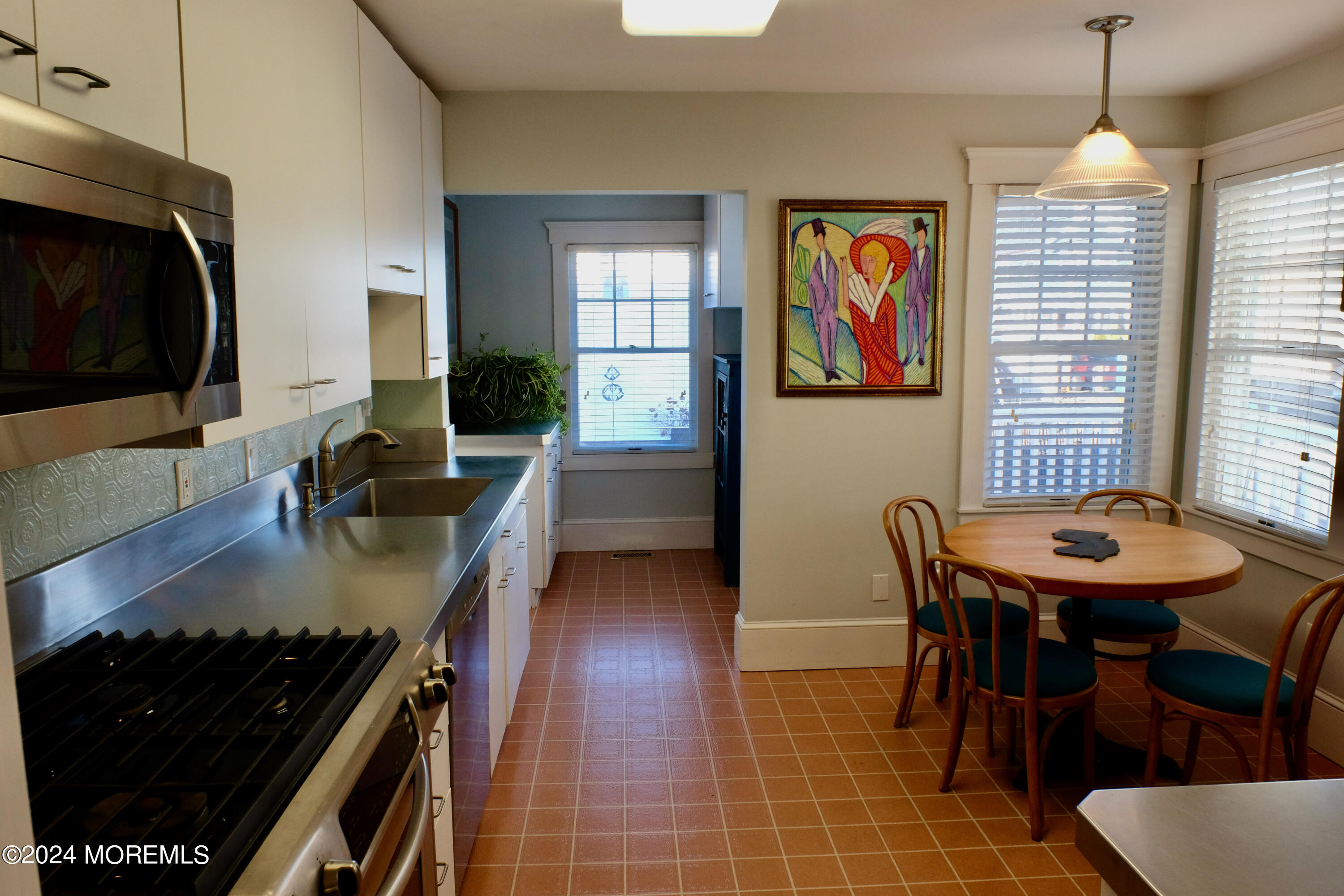 220 Lincoln Avenue, Unit 1 Avon-by-the-Sea, NJ 07717 - Photo 10 of 26 a kitchen with a stove a sink a dining table and chairs