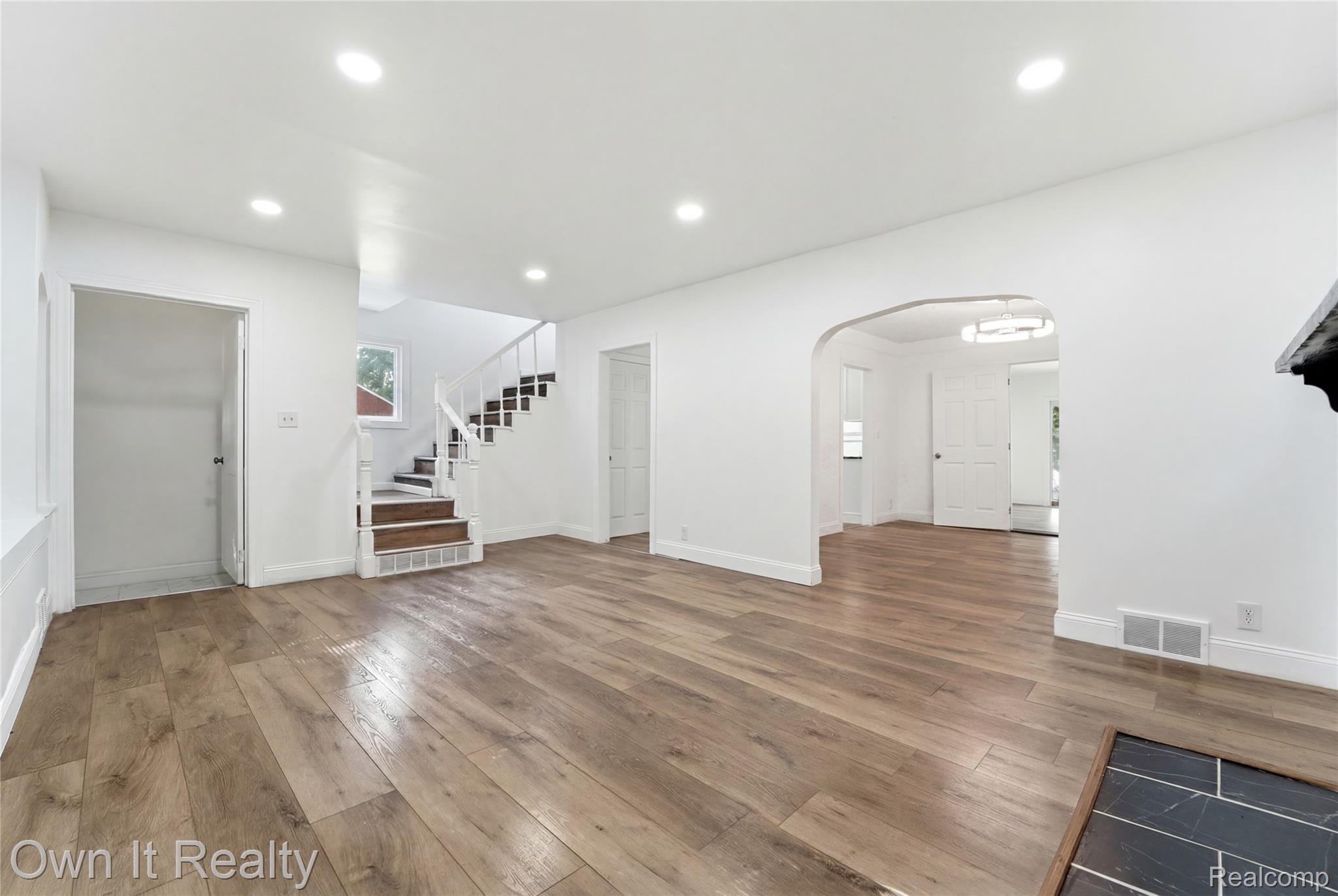 17351 Appoline Street Detroit, MI 48235 - Photo 3 of 34 Spacious interior featuring wood-finish flooring, white walls, recessed lighting, a staircase with white balusters and wood treads, and an arched doorway