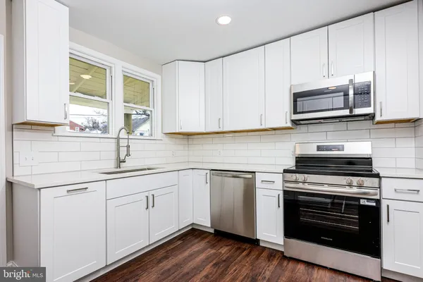 a kitchen with stainless steel appliances granite countertop a sink and a stove top oven with wooden floor