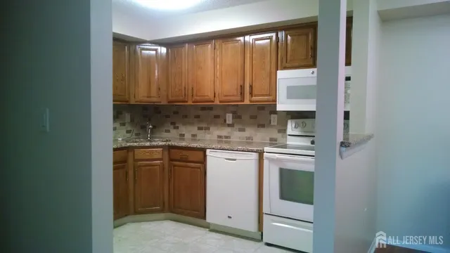a kitchen with granite countertop white cabinets and white appliances
