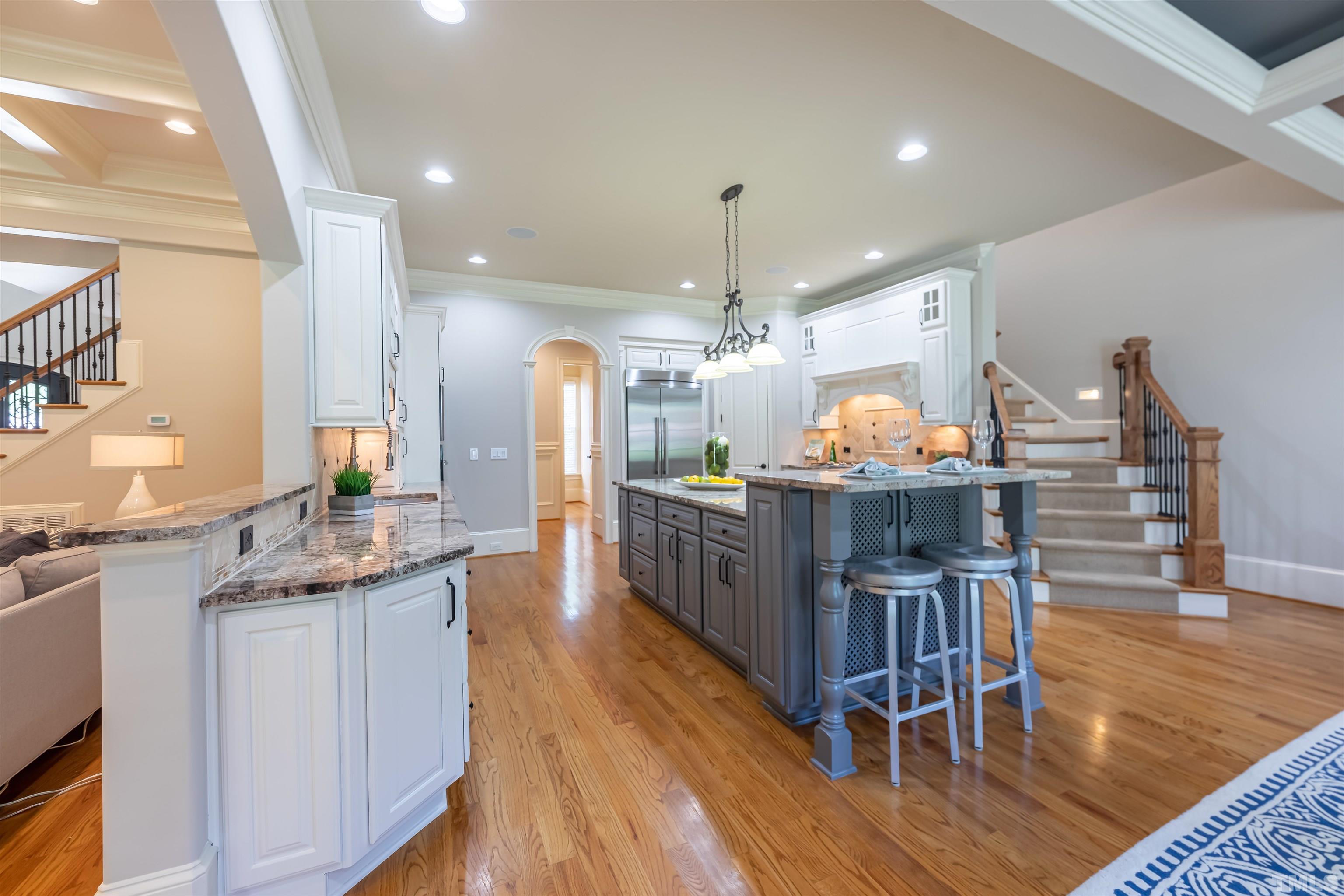 9805 Najma Street Raleigh, NC 27613 - Photo 12 of 29 a kitchen with stainless steel appliances kitchen island granite countertop a table chairs and a wooden floors