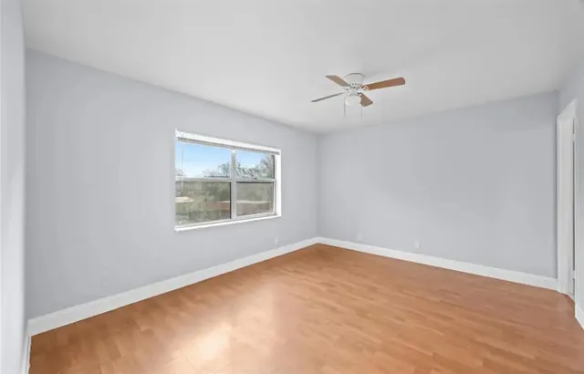 an empty room with a window and a ceiling fan