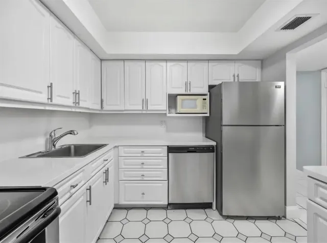 a kitchen with appliances a refrigerator and cabinets