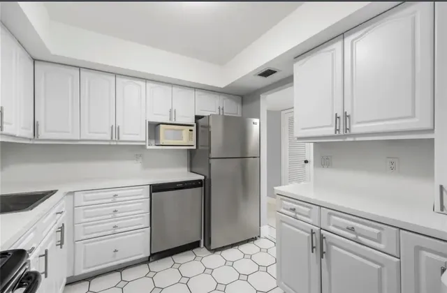 a kitchen with white cabinets and refrigerator