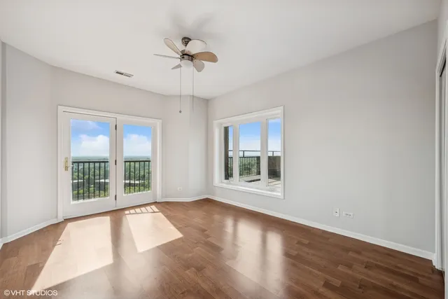 a view of an empty room with a window and wooden floor