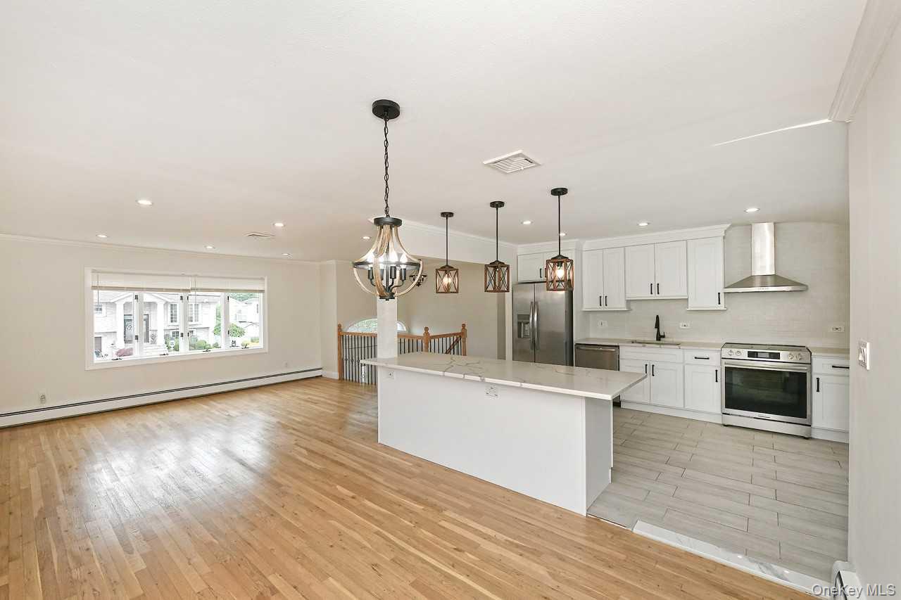 107 Beverly Road Massapequa, NY 11758 - Photo 9 of 41 a kitchen with stainless steel appliances kitchen island wooden floors and white cabinets