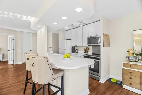 a kitchen with stainless steel appliances a white table chairs refrigerator and microwave