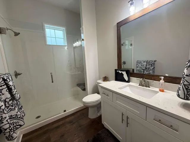 a bathroom with a sink a toilet a mirror and shower