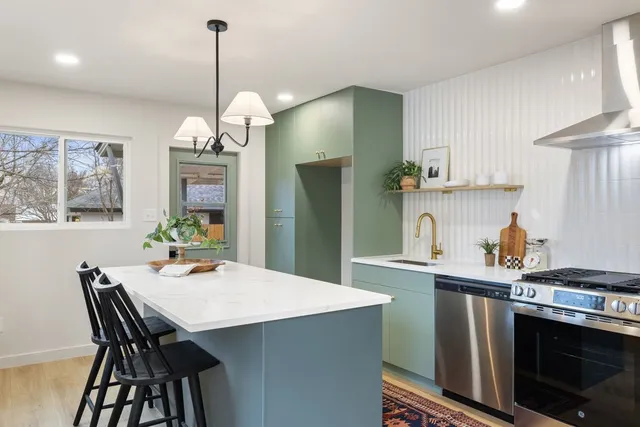 a kitchen with stainless steel appliances a dining table chairs and stove