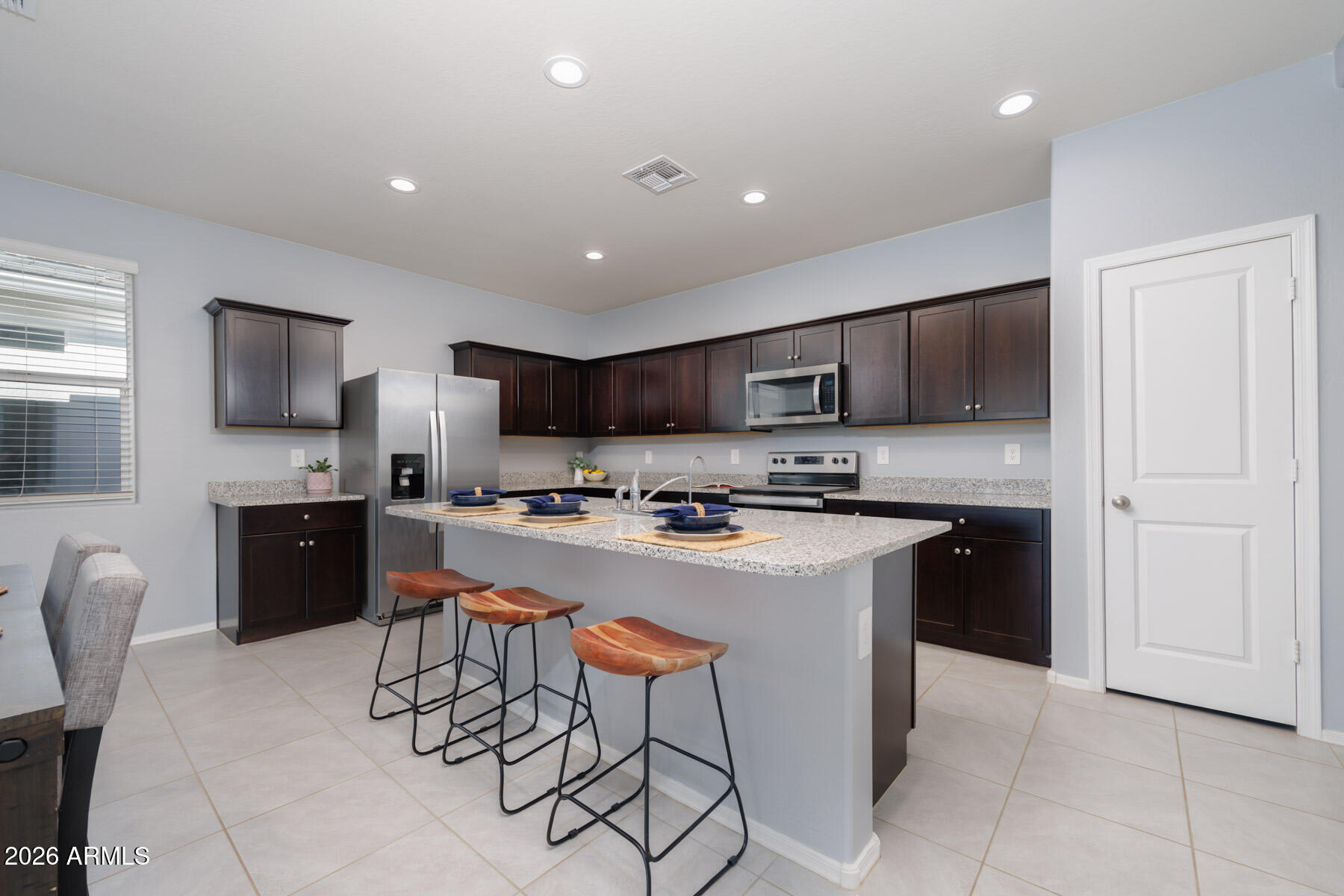 9381 Greenhouse Road Florence, AZ 85132 - Photo 9 of 35 a kitchen with stainless steel appliances granite countertop a stove a sink a refrigerator a microwave oven with a dining table and chairs