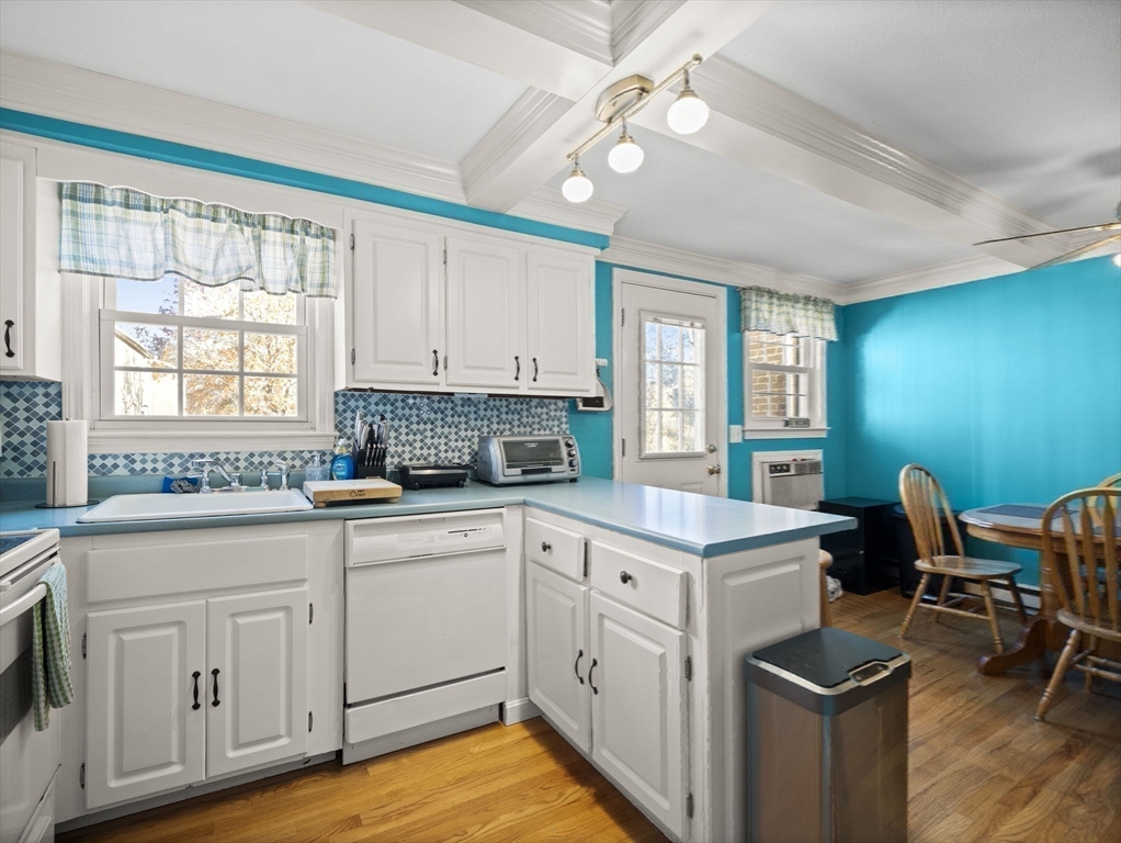 17 Cannongate Road, Unit 87 Tyngsborough, MA 01879 - Photo 12 of 39 a kitchen with a stove a sink and white cabinets with wooden floor