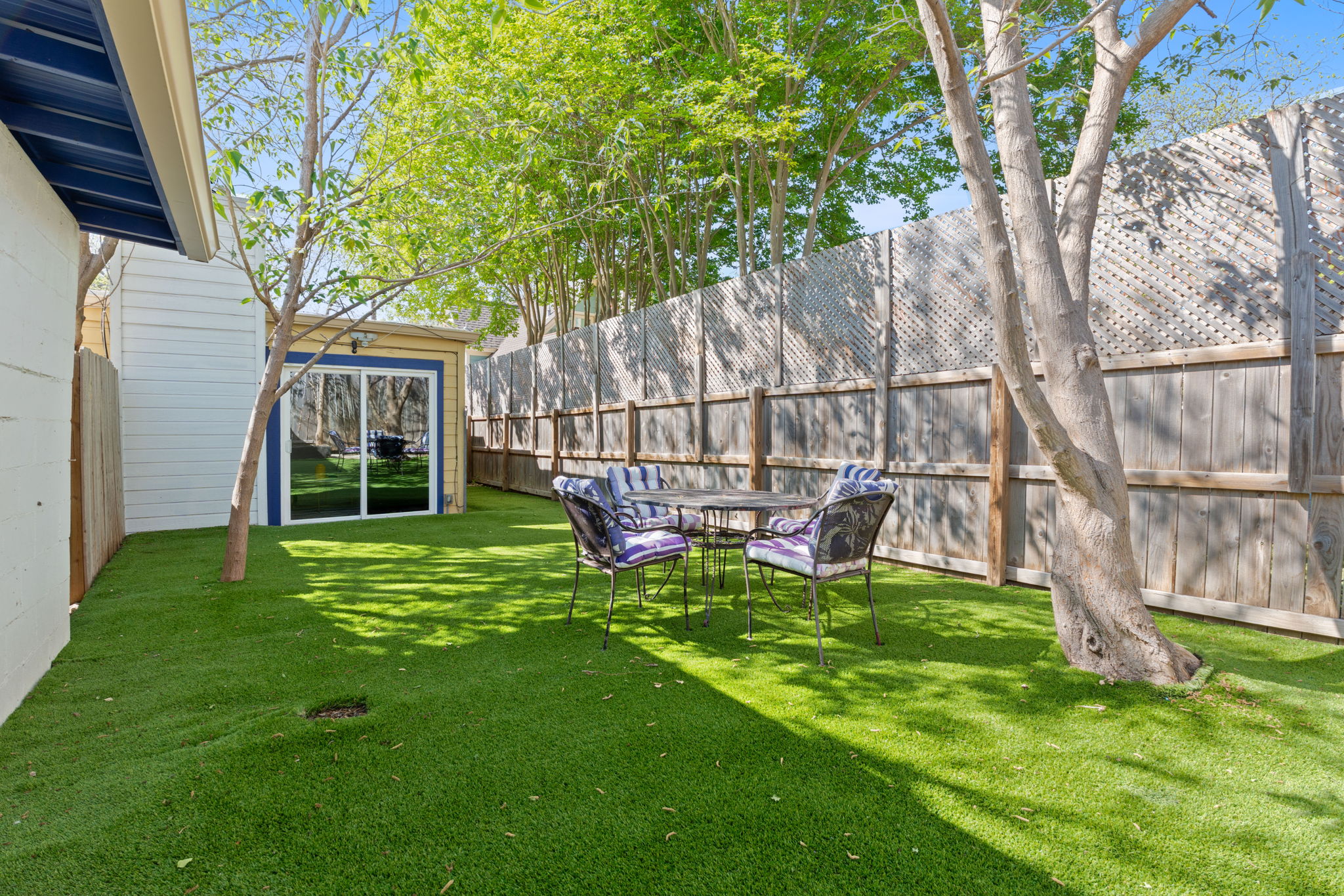 4611 Rosedale Avenue Austin, TX 78756 - Photo 26 of 35 A fully fenced backyard with a shaded patio creates private outdoor living space shared between the units — a rare extension of livable square footage in the heart of the city.